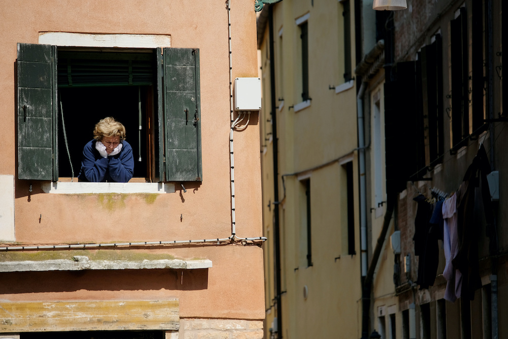 A woman looks out of an apartment window as Italians remain under lockdown to prevent the spread of the coronavirus disease (Covid-19) in Venice, Italy April 4, 2020. — Reuters pic