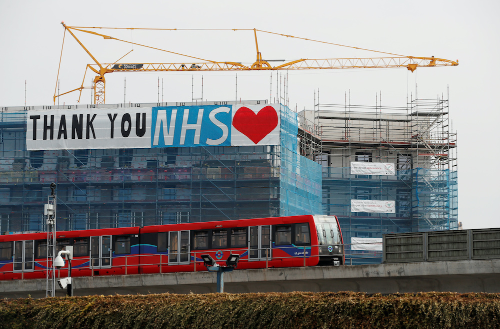 A Docklands Light Railway train is seen passing a banner on a construction site thanking the NHS, as the spread of the coronavirus disease (Covid-19) continues, London, Britain, April 8, 2020. u00e2u20acu201d Reutersnn