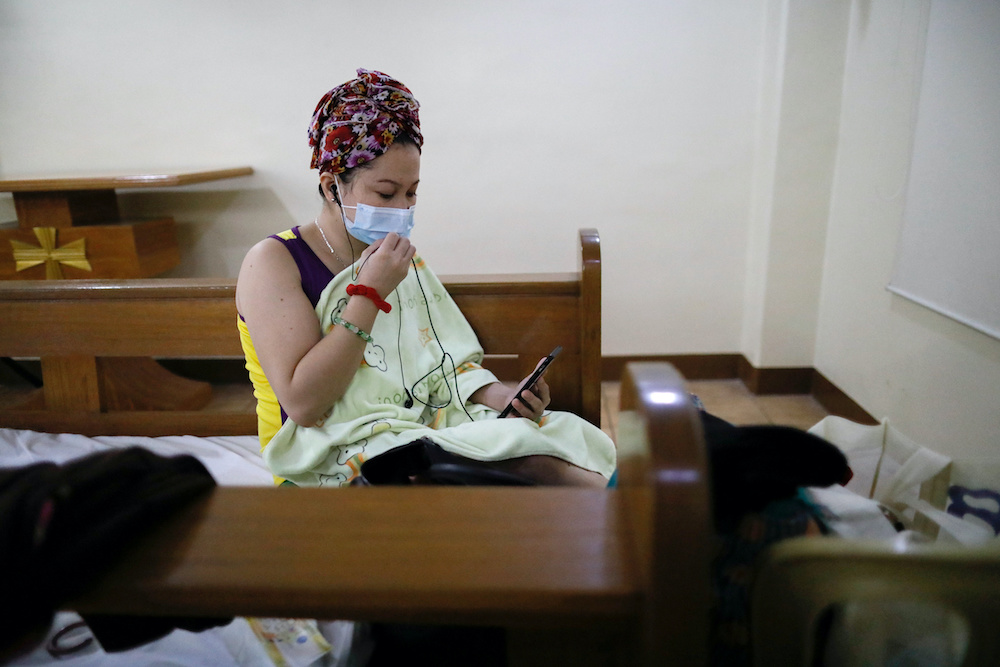 A hospital worker wearing a protective face mask video calls a relative while at a funeral chapel that temporarily shelters health workers from a nearby hospital taking in coronavirus disease (Covid-19) patients, in Makati City, Metro Manila, Philippines 