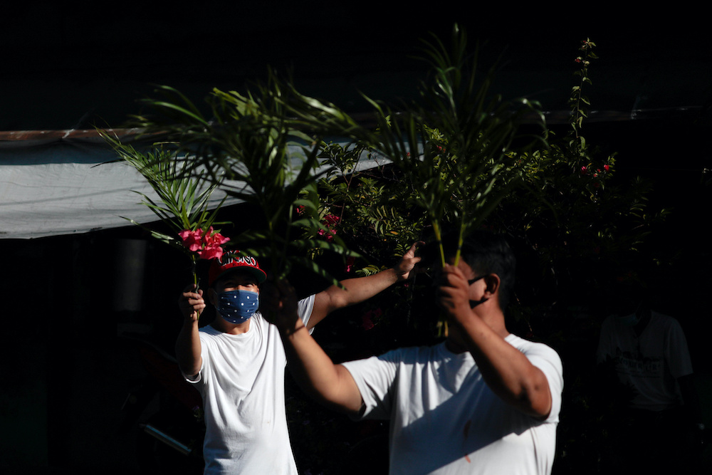 Filipino Catholics wave palm fronds outside their homes as they wait for the blessing of a priest roaming neighbourhoods to celebrate Palm Sunday amid the lockdown to contain the coronavirus disease (Covid-19), in Manila, Philippines, April 5, 2020. u00e2u20acu201d R