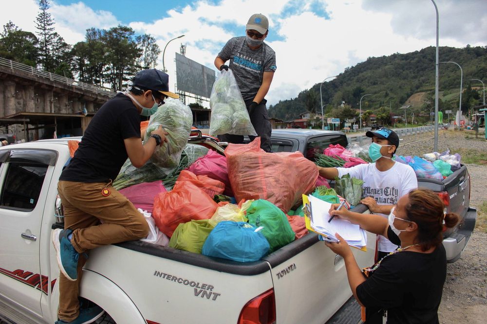 Youth activist and vegetable entrepreneur Azizul Julirin, (second left) with his friends loading a variety of vegetables into a vehicle to be transported to Kota Kinabalu to fulfill demands during the Movement Control Order, in Kundasang, March 28, 2020. 