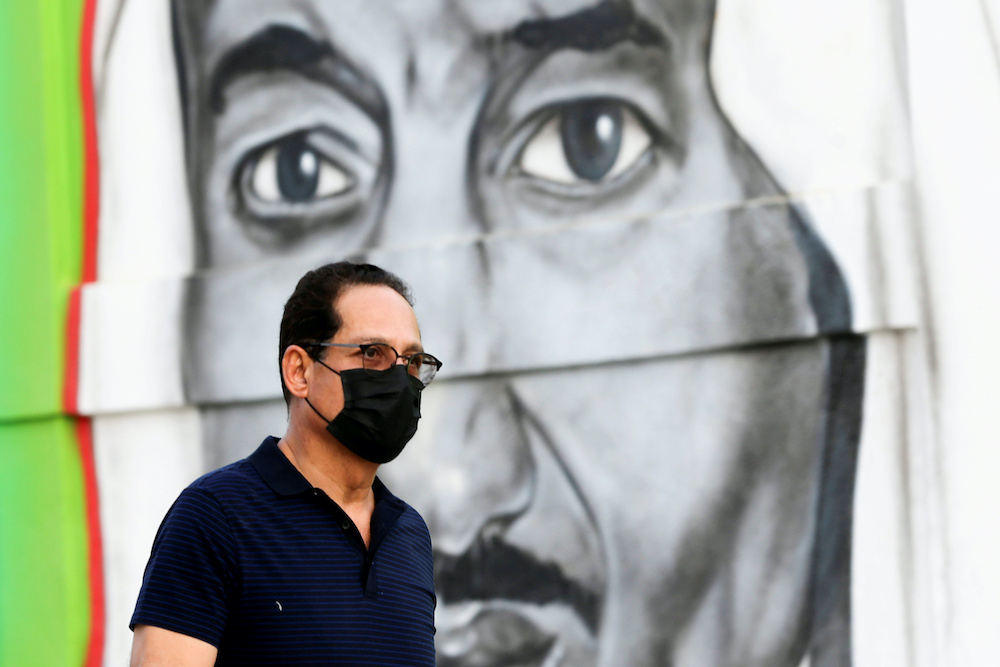 A Saudi man walks past a poster depicting Saudi King Salman bin Abdulaziz, after a curfew was imposed to prevent the spread of the coronavirus disease, in Riyadh, Saudi Arabia March 25, 2020. u00e2u20acu2022 Reuters picnnn