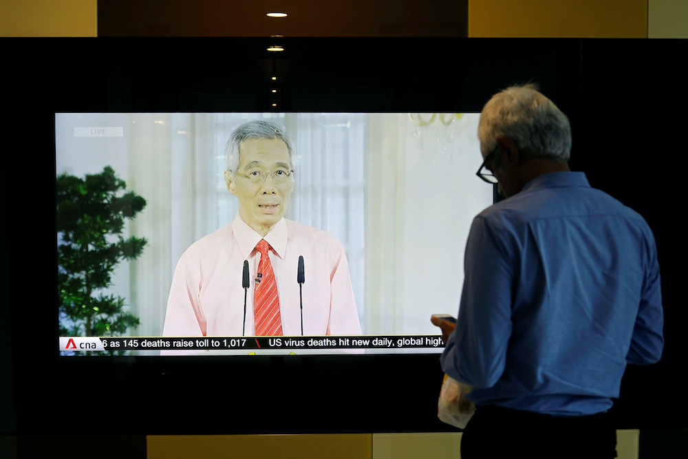 A man stands in front of a screen showing a telecast of Singaporeu00e2u20acu2122s Prime Minister Lee Hsien Loong addressing the outbreak of coronavirus disease (Covid-19), at the central business district in Singapore, April 3, 2020. u00e2u20acu201d Reuters picnnn