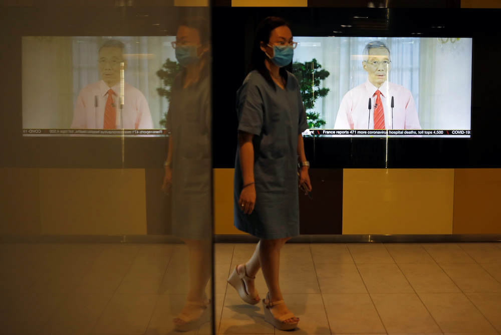 A woman with a face mask walks past a screen showing a telecast of Singaporeu00e2u20acu2122s Prime Minister Lee Hsien Loong addressing the outbreak of coronavirus disease (Covid-19), at the central business district in Singapore, April 3, 2020. u00e2u20acu201d Reuters picnnn