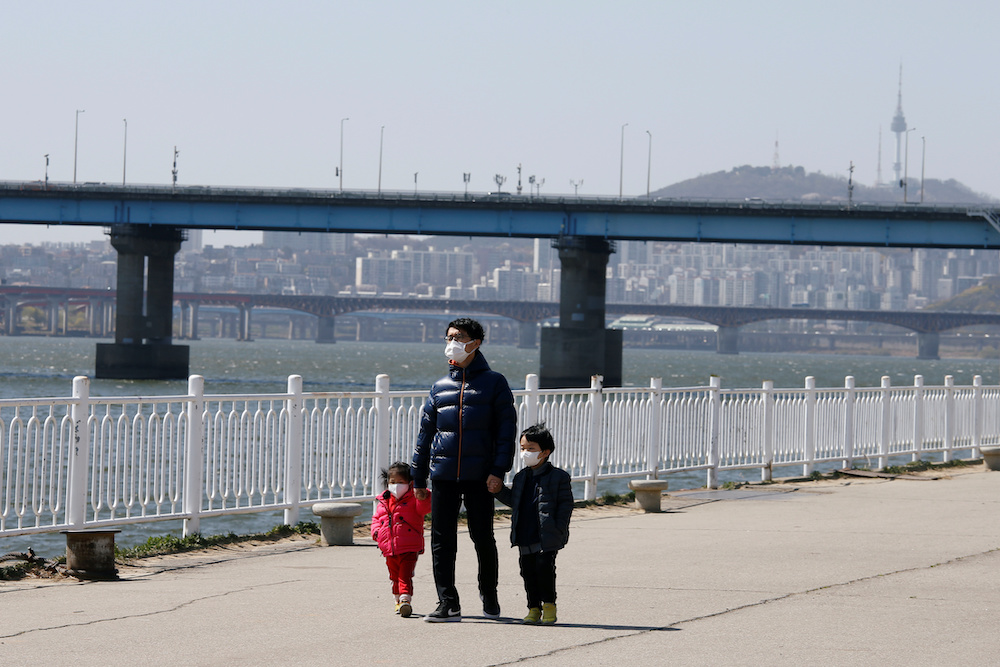 A man and children wearing masks to protect against contracting the coronavirus disease (Covid-19) take a walk at a Han River Park in Seoul, South Korea April 4, 2020.  u00e2u20acu201d Reutersnn