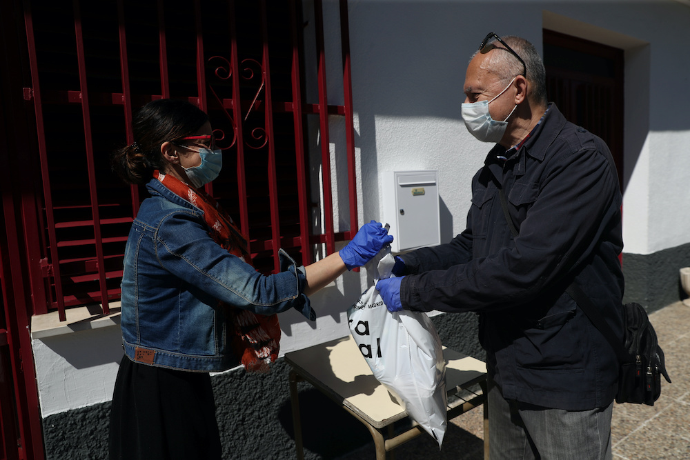 A woman is handed a bag with food outside San Juan de Dios meal centre, which had to adjust its operation to prevent Covid-19 contagion among its users by providing them with ready to eat food, during the coronavirus disease (Covid-19) outbreak, in Ciempo