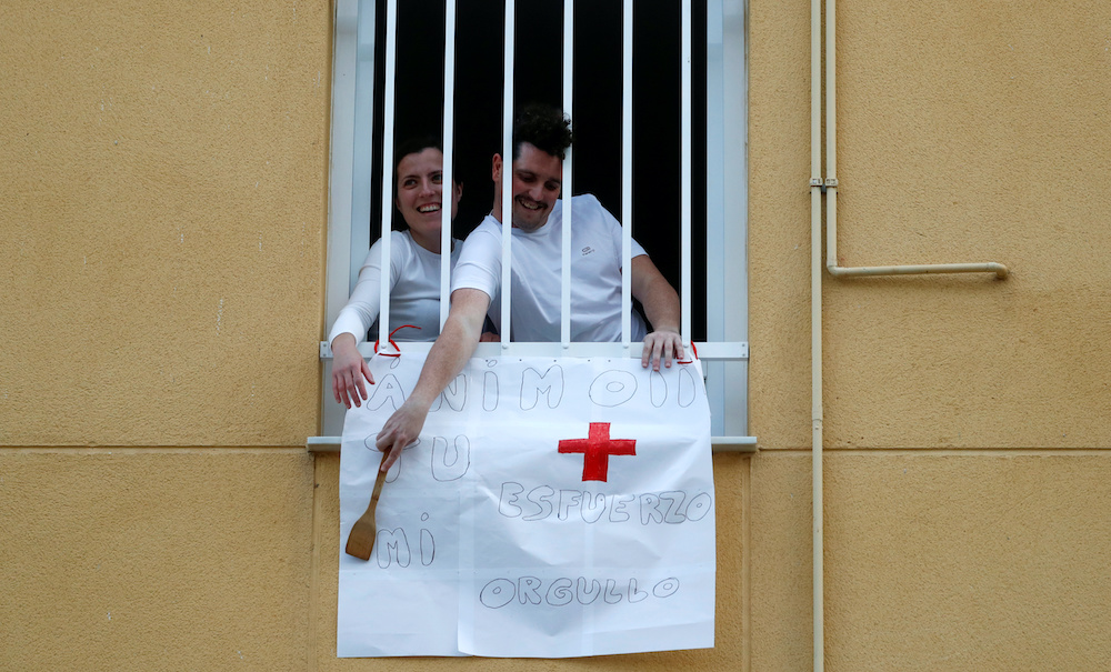 Two people gesture as they lean out of their window after the applause in honour of healthcare workers, amid the coronavirus disease (Covid-19) outbreak, in downtown Ronda, southern Spain, April 7, 2020. u00e2u20acu201d Reutersnn