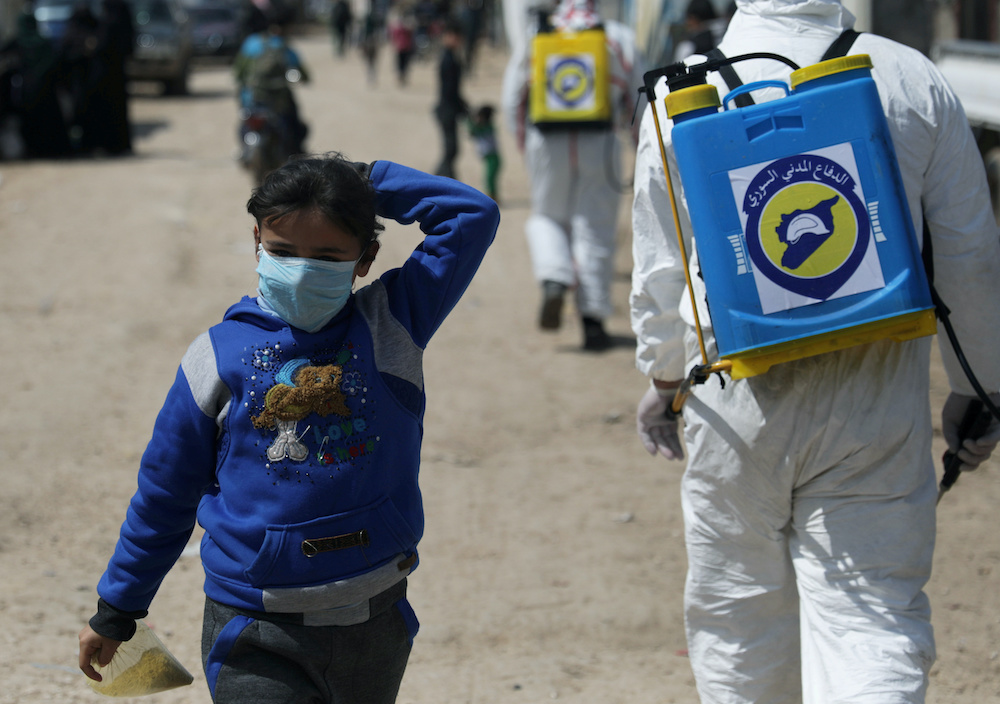 An internally displaced Syrian girl wears a face mask as members of the Syrian Civil defence sanitize the Bab Al-Nour internally displaced persons camp, to prevent the spread of coronavirus disease (Covid-19) in Azaz, Syria March 26, 2020. u00e2u20acu201d Reuters pic