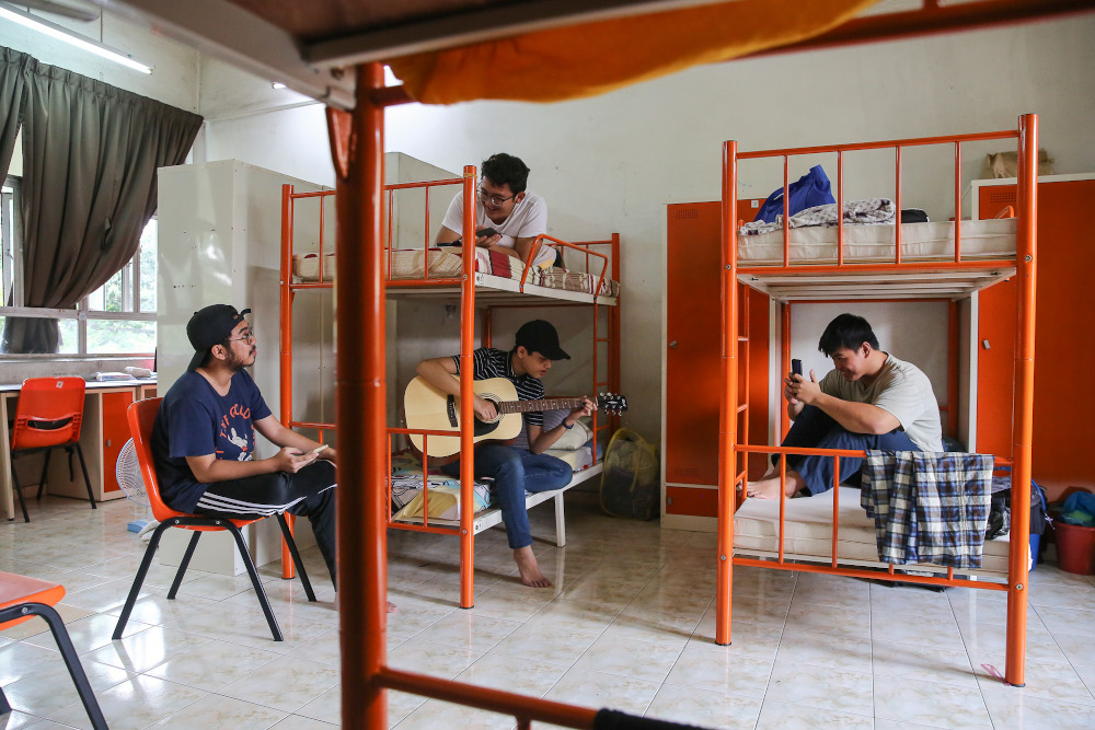 UiTM Law students, Ahmad Daniel Nor Amin plays a guitar as he entertains his friend inside their room during the movement control order (MCO) at the Kolej Perindu in Shah Alam April 15, 2020. u00e2u20acu201d Picture by Yusof Mat Isa