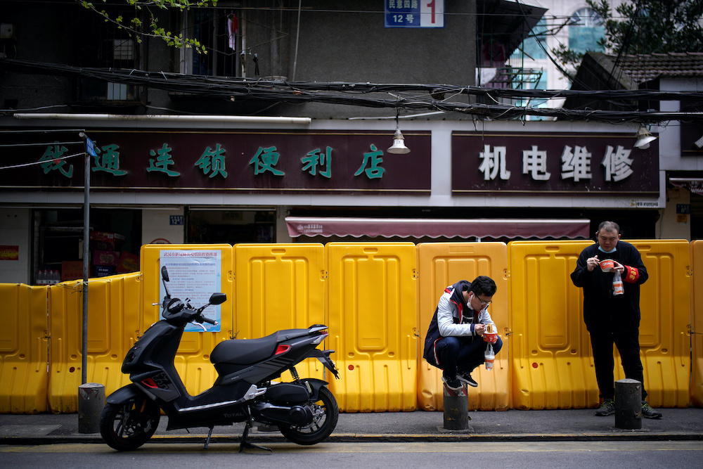 People wearing face masks eat u00e2u20acu02dcRegan Noodleu00e2u20acu2122, Wuhanu00e2u20acu2122s signature hot dried noodles, for breakfast at a residential area blocked by barriers in Wuhan, Hubei province, the epicentre of China's coronavirus disease (Covid-19) outbreak, April 2, 2020.u00e2u20acu201d 