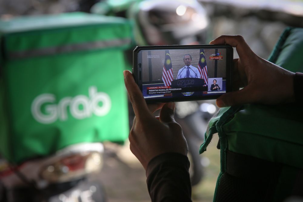 Food delivery rider watching the live telecast of Prime Minister Tan Sri Muhyiddin Yassinu00e2u20acu2122s announcement of a movement control order extension due to the Covid-19 pandemic in Shah Alam, April 10, 2020. u00e2u20acu201d Picture by Yusof Mat Isa