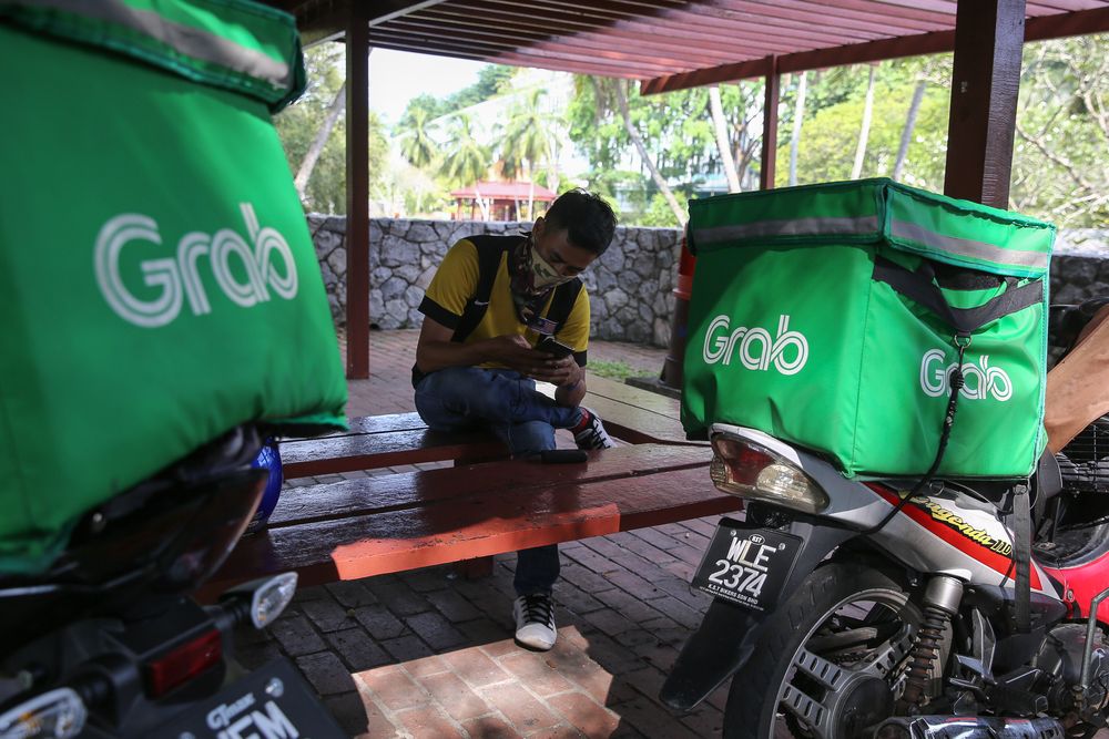 Food delivery rider watching the live telecast of Prime Minister Tan Sri Muhyiddin Yassinu00e2u20acu2122s announcement of a movement control order extension due to the Covid-19 pandemic in Shah Alam, April 10, 2020. u00e2u20acu201d Picture by Yusof Mat Isa