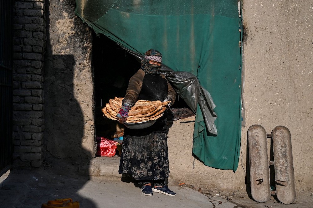Afghan Zainab Sharifi, 45, baker, poses for a photograph holding loaves of bread outside her bakery in Kabul on April 23, 2020 during the Covid-19 pandemic. Ahead of May Day on May 1, 2020. u00e2u20acu201d AFP picnn
