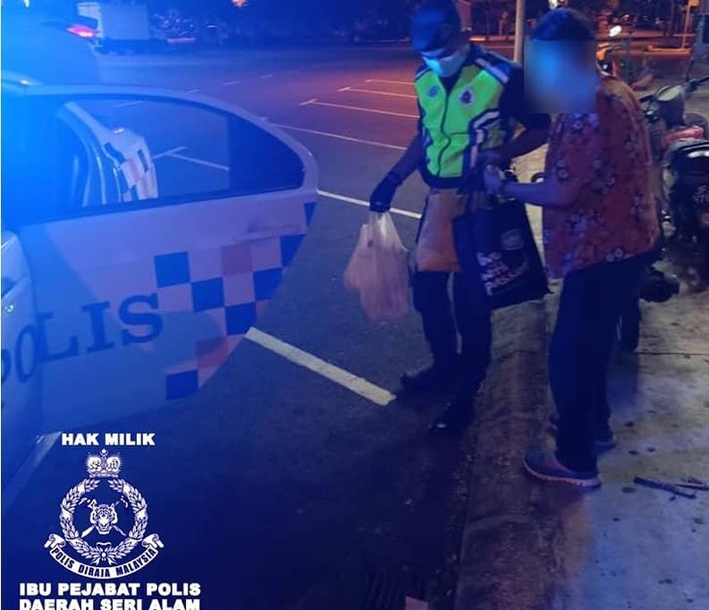 One of the Seri Alam district police members helping the elderly woman get into the car before sending her home. u00e2u20acu201d Picture by Facebook/PoliceDaerahSeriAlam