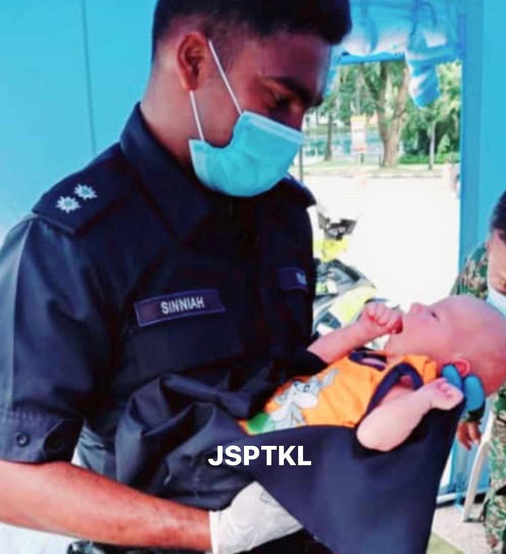 Inspector Sinniah holding the fully-clothed baby in his arms. — Picture via Facebook/JSPTKL