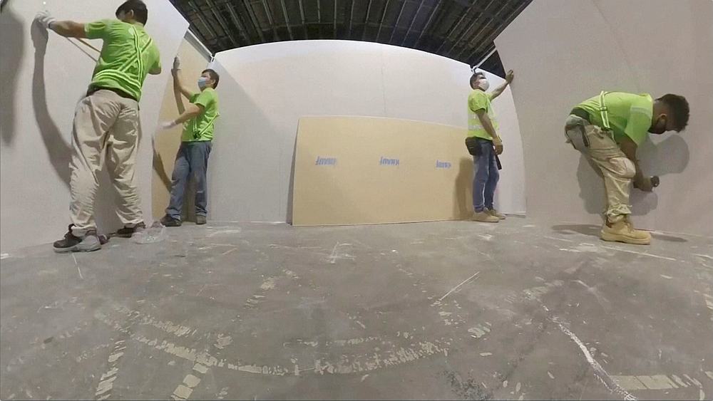 Workers set up partitions inside Changi Exhibition Centre, a repurposed community isolation facility for Covid-19 patients in Singapore, in this undated video image. CEC Facility Executive Committee handout via Reuters