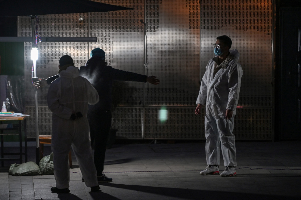 A man wearing a protective suit sprays disinfectant on another man next to a residential compound in Wuhan, in Chinau00e2u20acu2122s central Hubei province April 11, 2020. u00e2u20acu201d AFP pic 