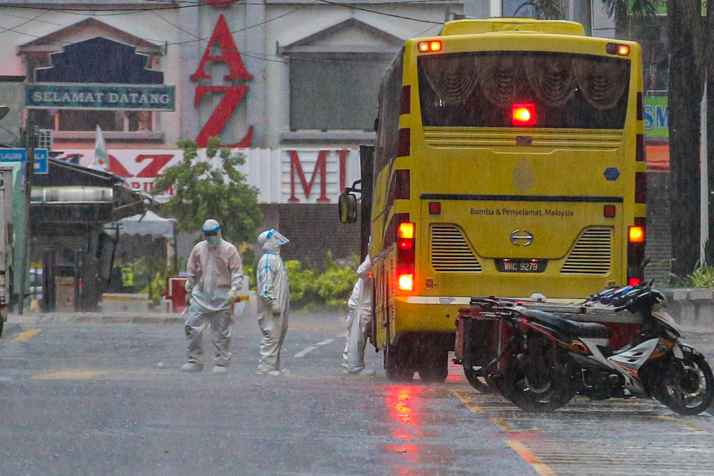 Health workers are seen at Menara City One during heavy rain after bringing Menara City One residents on board the Fire and Rescue Department (Bomba) bus April 22, 2020. u00e2u20acu201d Picture by Hari Anggara