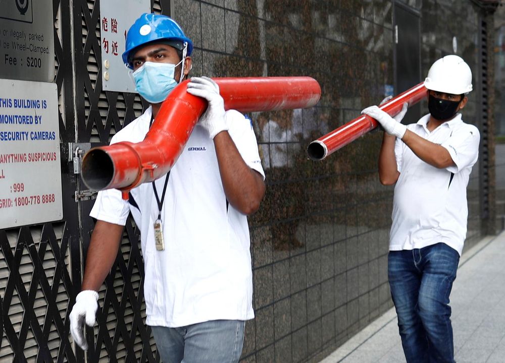 Construction workers wearing masks in precaution of the coronavirus outbreak carry pipes as they pass a building in the Central Business District in Singapore, February 18, 2020. u00e2u20acu201d Reuters pic
