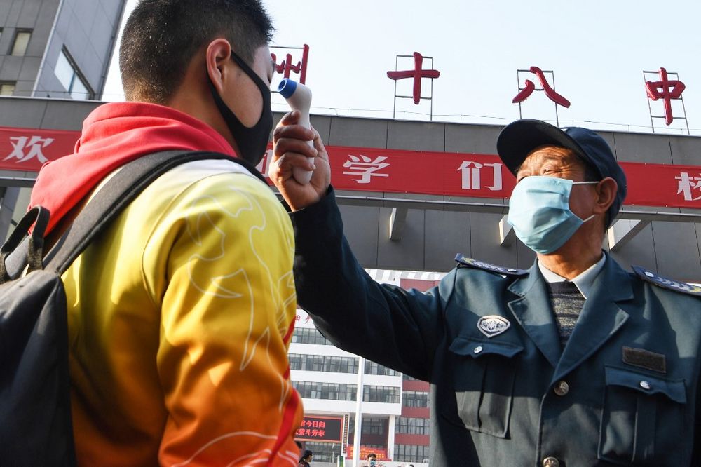 A staff member checks the body temperature of a student as grade three high school students return after the term opening was delayed due to the Covid-19 coronavirus outbreak, in Bozhou in Chinau00e2u20acu2122s eastern Anhui province on April 7, 2020. u00e2u20acu201d AFP pic
