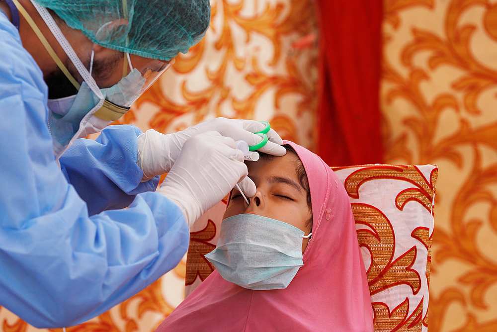 A health worker wearing protective gear takes a nose-swab from a girl, at the walk-through screening and testing facility for Covid-19 in Karachi, Pakistan April 21, 2020. u00e2u20acu201d Reuters pic