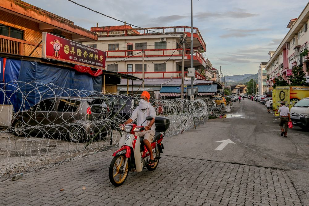 A motorcyclist rides past barbed wire fencing in Selayang Baru, amid the enhanced movement control order April 26, 2020. u00e2u20acu2022 Picture by Firdaus Latif