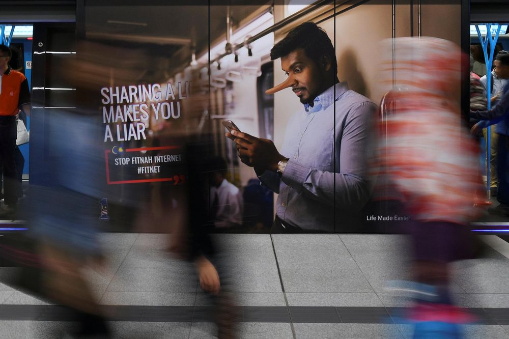 File picture shows commuters walking past an advertisement discouraging the dissemination of fake news at a train station in Kuala Lumpur, March 28, 2018. u00e2u20acu201d Reuters pic