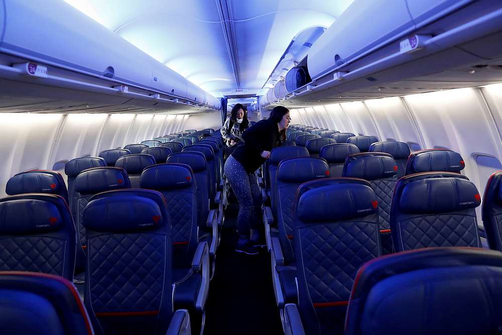 Air travellers grab carry-on luggage behind rows of empty seats aboard a Delta flight from New York's JFK International Airport to San Francisco, California March 17, 2020. u00e2u20acu201d Reuters pic