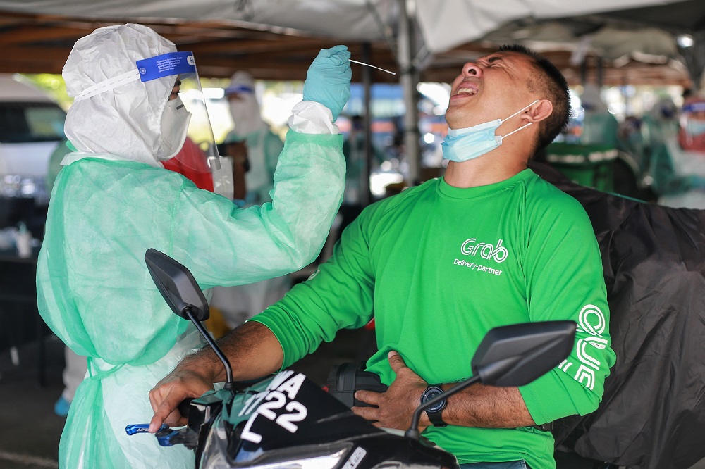 A health worker collects a coronavirus test sample from a food delivery rider at the Gombak Land and District office April 22, 2020. u00e2u20acu2022 Picture by Ahmad Zamzahuri