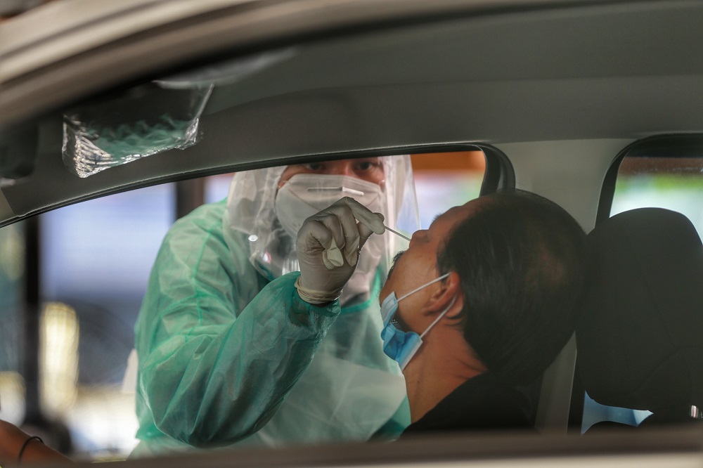 A health worker collects a coronavirus test sample from a man at the Gombak Land and District office April 22, 2020. u00e2u20acu2022 Picture by Ahmad Zamzahuri