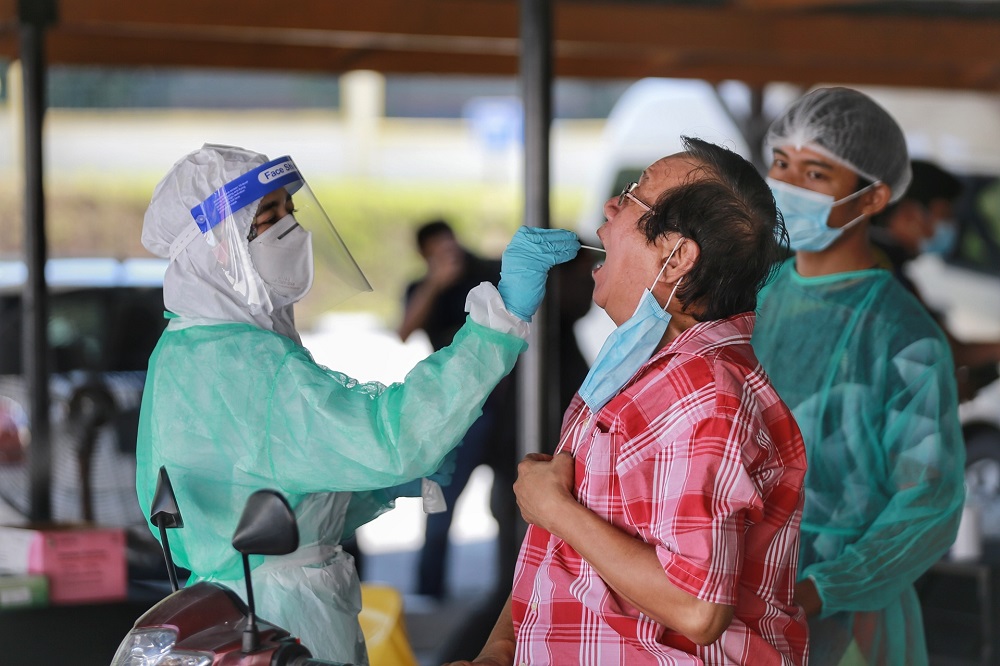 A health worker collects a coronavirus test sample from a man at the Gombak Land and District office April 22, 2020. u00e2u20acu2022 Picture by Ahmad Zamzahuri