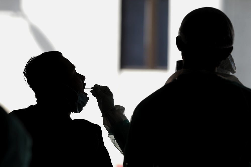 A health worker collects a coronavirus test sample from a man at the Gombak Land and District office April 22, 2020. u00e2u20acu2022 Picture by Ahmad Zamzahuri