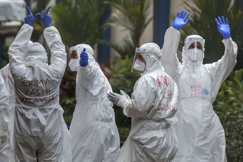 Health workers wave to members of the media at Menara City One in Kuala Lumpur April 14, 2020. u00e2u20acu201d Picture by Ahmad Zamzahuri