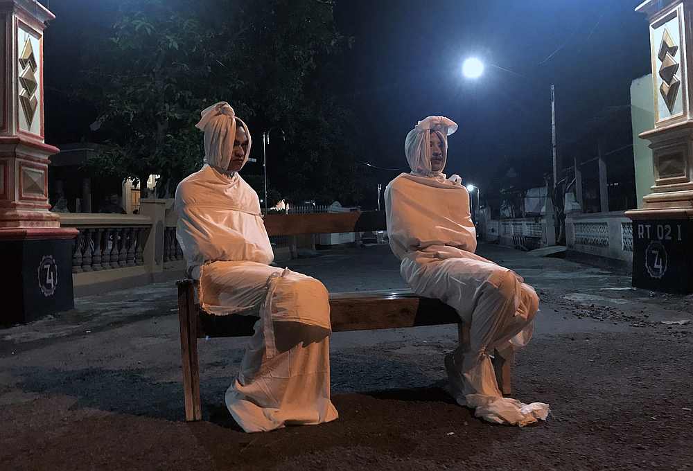 Volunteers Deri Setyawan, 25, and Septian Febriyanto, 26, sit on a bench as they play the role of 'pocong,' or known as 'shroud ghost,' to make people stay at home in Kepuh village, Central Java, Indonesia, April 1, 2020. u00e2u20acu201d Reuters pic