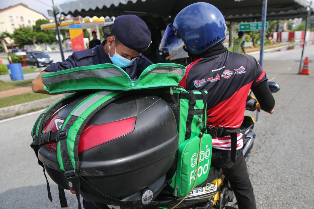 A police personnel conducts checks on a food delivery rider in Section 7, Shah Alam April 15, 2020. u00e2u20acu201d Picture by Yusof Mat Isa