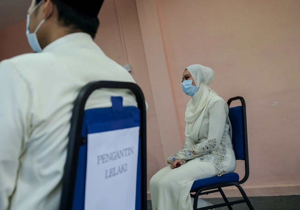 A couple observe social distancing guidelines before performing their u00e2u20acu02dcnikahu00e2u20acu2122 vows at the Ipoh District Islamic Religious Office April 22, 2020. u00e2u20acu201d Picture by Farhan Najib