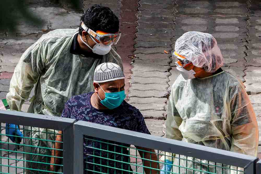 Medical personnel stand behind a migrant worker as they wait to assist him onto an ambulance at a dormitory amid the Covid-19 outbreak in Singapore April 28, 2020. u00e2u20acu201d Reuters pic