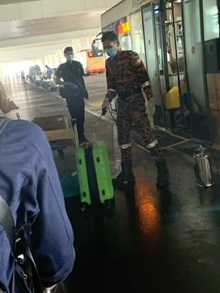 A fireman fumigating the luggage of Malaysian returnees. — Picture via Facebook Shacind Ananthan