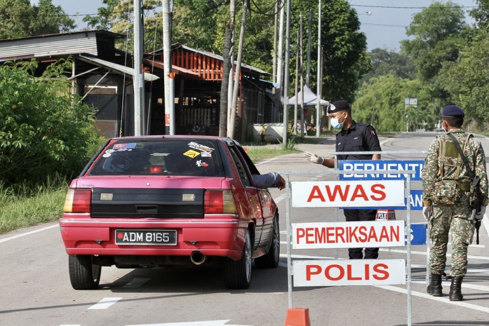 Police and Armed Forces personnel man a roadblock on the road from Benut leading to the two areas in Simpang Renggam where the enhanced movement control order was lifted today. u00e2u20acu201d Picture by Ben Tan