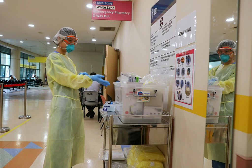 A staff member of Tan Tock Seng Hospital's emergency department putting on protective gear. A new study suggests that the measures taken to keep healthcare workers safe have successfully ensured that they do not get infected with the coronavirus. u00e2u20acu2022 TODA