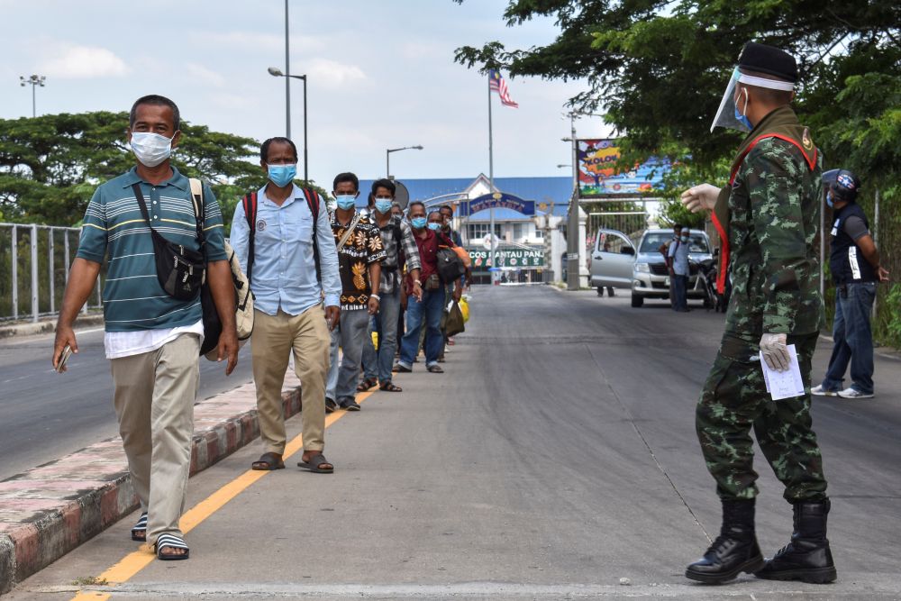 Thai people wearing face masks who returned to their hometown due to the spread of the coronavirus disease walk in line at Thai-Malaysia border Sungai Kolok district, Narathiwat April 18, 2020. u00e2u20acu201d Reuters pic