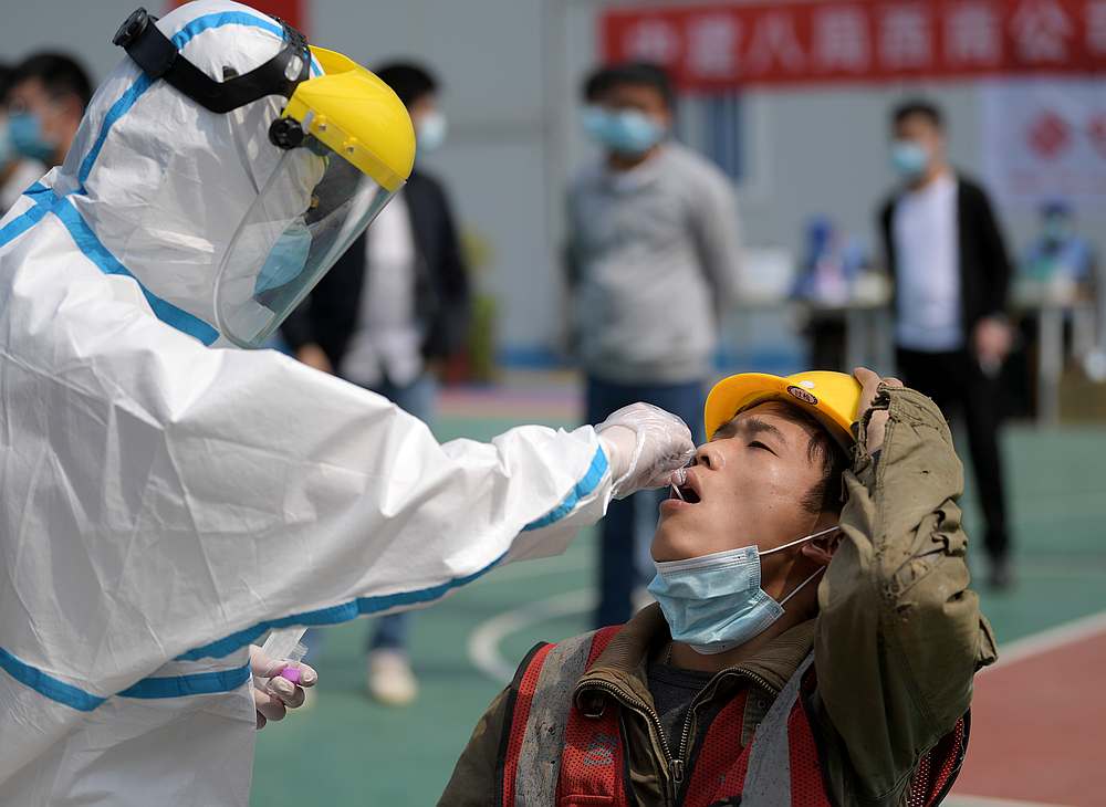A worker in a protective suit collects a swab from a construction worker in Wuhan, Hubei province, China April 7, 2020. u00e2u20acu201d China Daily pic via Reuters