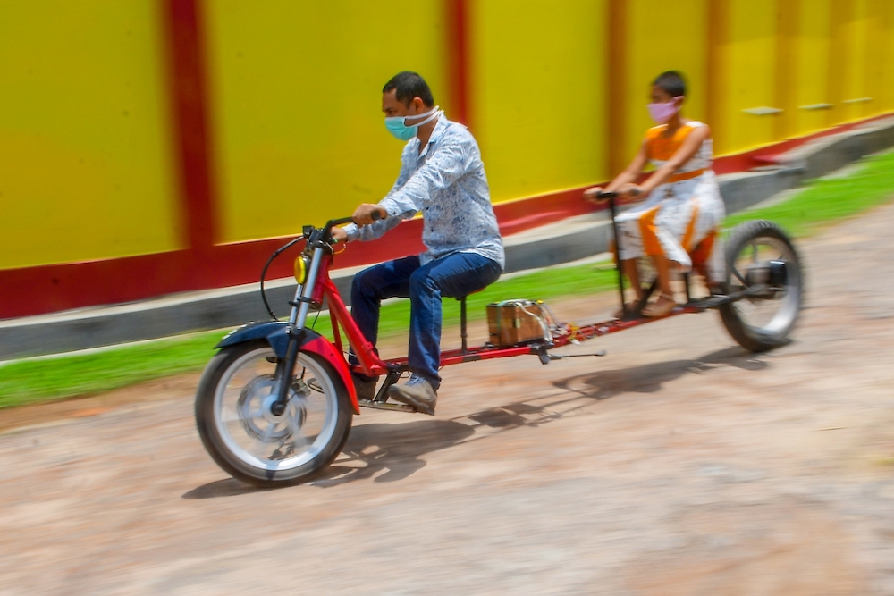 Self-made automobile engineer Partha Saha (left) tries his modified bike designed for social distancing as a preventive measure against the spread of the Covid-19. u00e2u20acu201d AFP pic