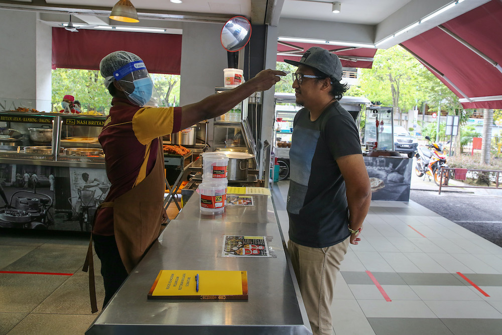 A worker checks the body temperature of a customer at Khulafa Restaurant in Shah Alam May 2, 2020. u00e2u20acu201d Picture by Yusof Mat Isa