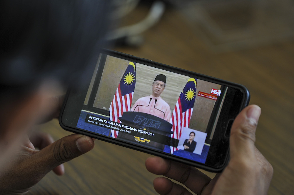 A man watches the live telecast of Prime Minister Tan Sri Muhyiddin Yassinu00e2u20acu2122s special address about the conditional movement control order in Kuala Lumpur May 10, 2020. u00e2u20acu201d Picture Shafwan Zaidon