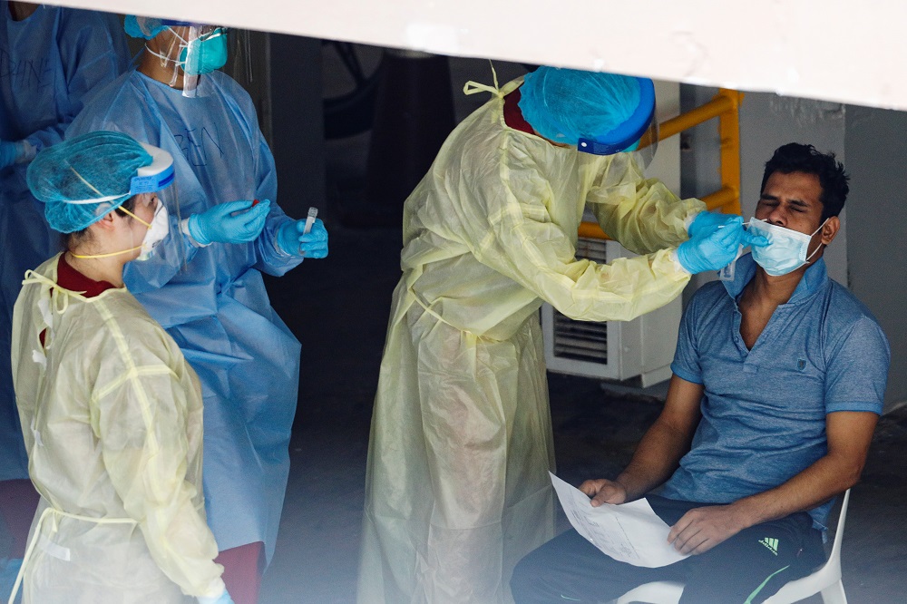 A migrant worker undergoes a nose swab test as medical workers look on at a dormitory amid the coronavirus disease outbreak in Singapore April 28, 2020. u00e2u20acu201d Reuters pic