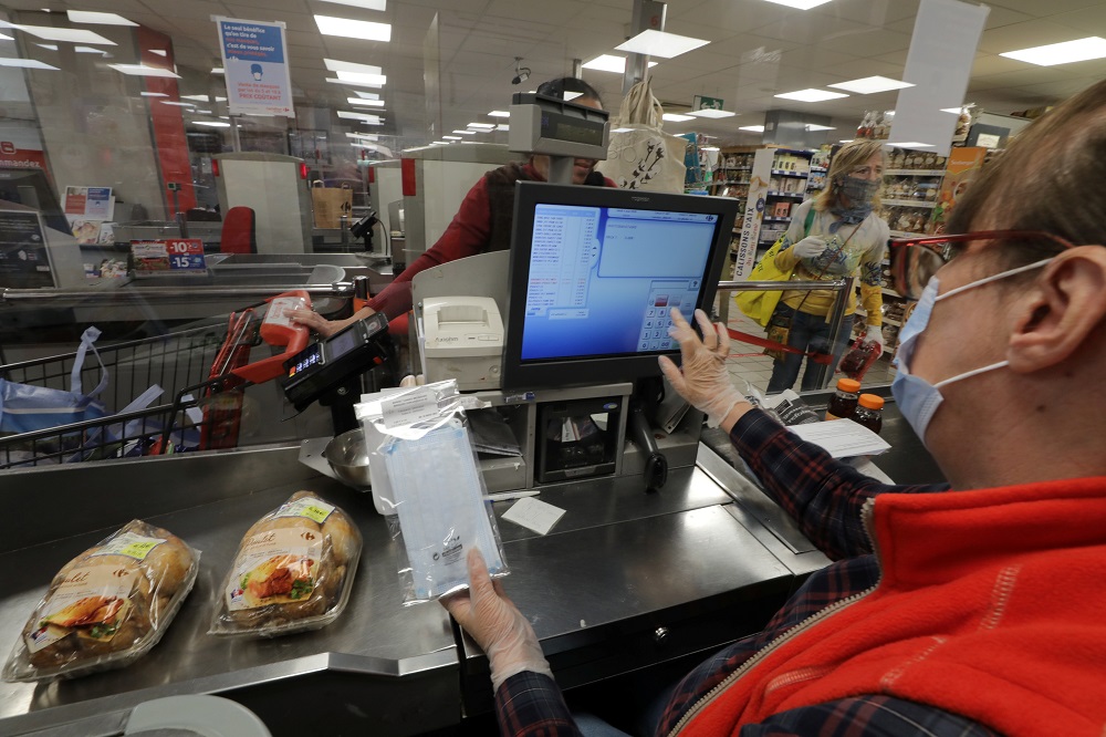 A cashier wearing a protective face mask holds a protective face mask on sale as she serves a customer at a Carrefour market in Cannes during the outbreak of the coronavirus disease in France May 4, 2020. u00e2u20acu201d Reuters pic