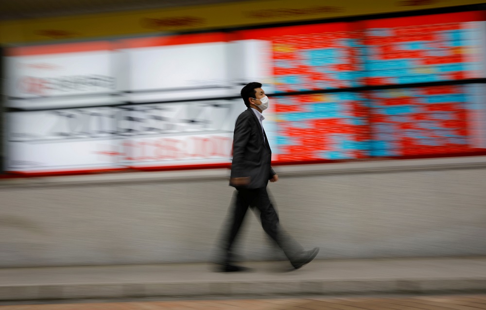 A man wearing a protective face mask, following the coronavirus disease outbreak, walks in front of a stock quotation board outside a brokerage in Tokyo May 18, 2020. u00e2u20acu201d Reuters pic