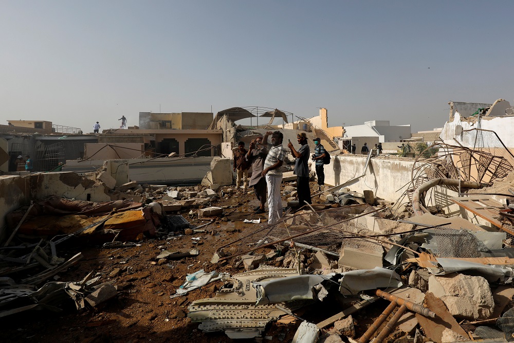 People stand on a roof of a house amidst debris of a passenger plane, crashed in a residential area near an airport in Karachi May 22, 2020. u00e2u20acu201d Reuters pic
