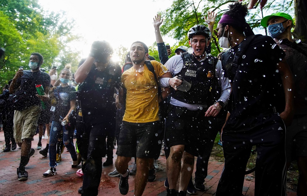 US Secret Service uniformed division officers detain a demonstrator as other protestors throw water at them during a protest march on the White House against the death of African-American man George Floyd, in Washington May 29, 2020. — Reuters pic